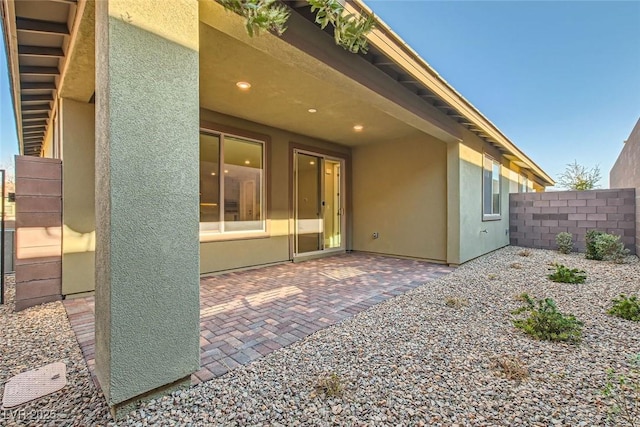 rear view of house featuring a patio area, fence, and stucco siding