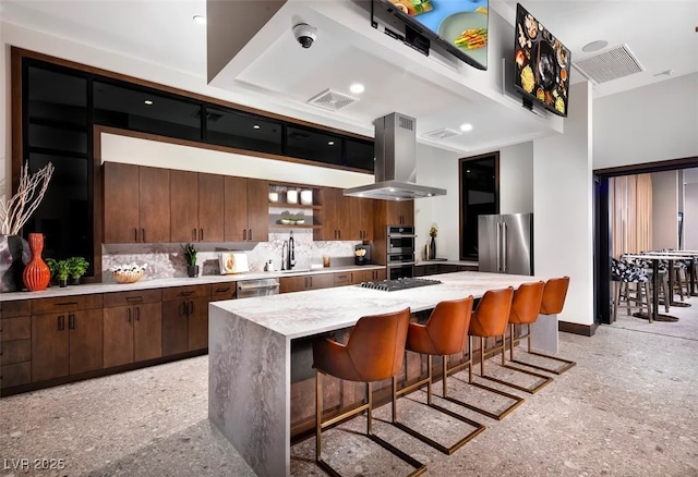 kitchen featuring stainless steel appliances, a breakfast bar, a kitchen island, light countertops, and island exhaust hood