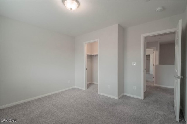 unfurnished bedroom with a spacious closet, a closet, and carpet flooring