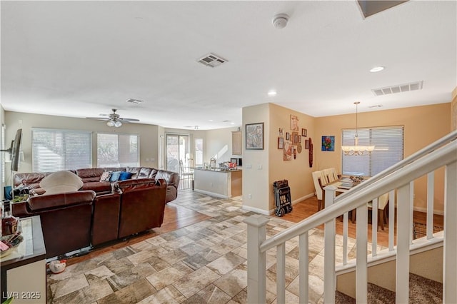 living room with ceiling fan with notable chandelier