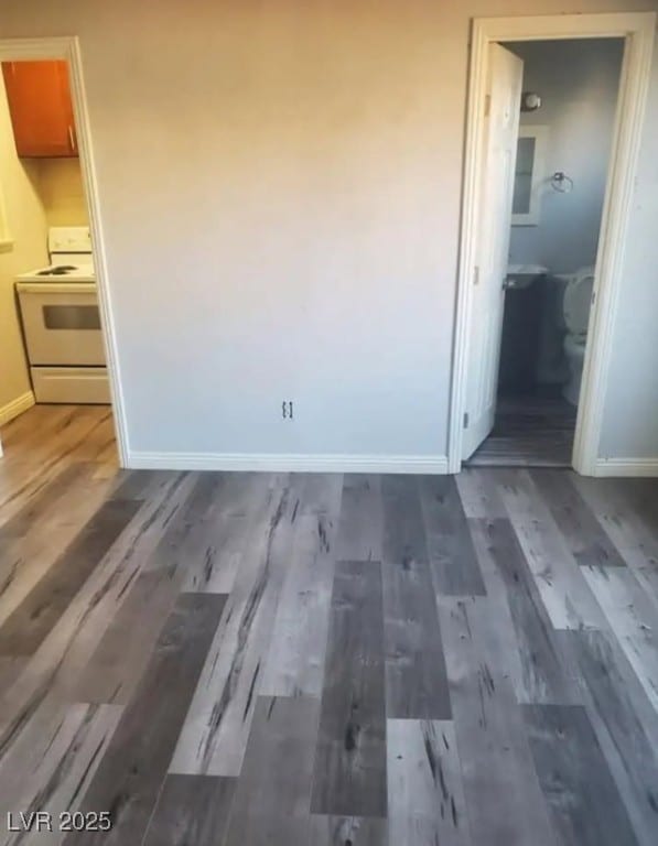 interior space with connected bathroom, baseboards, and wood finished floors