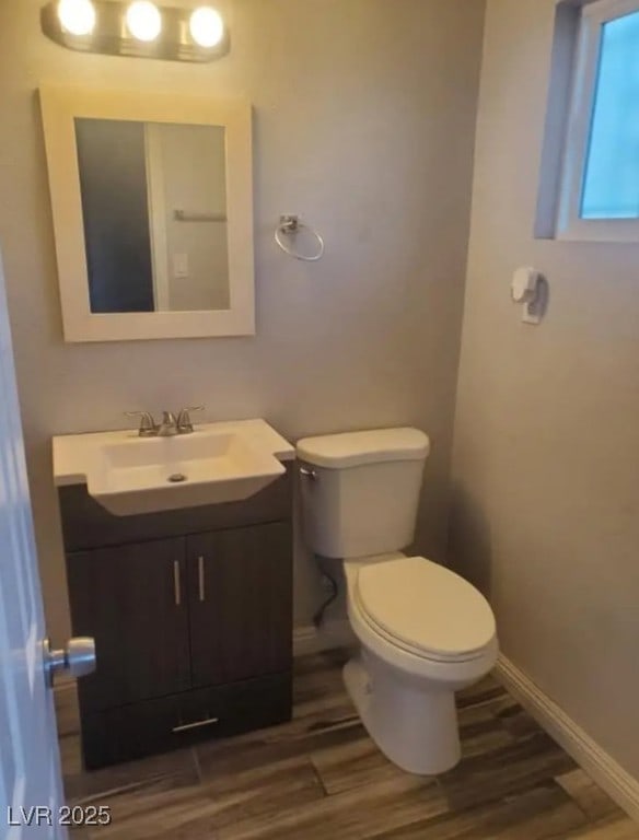 bathroom featuring toilet, wood finished floors, vanity, and baseboards