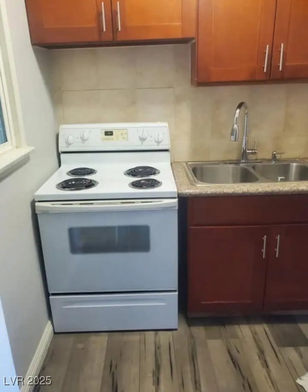 kitchen with dark wood-style flooring, white electric stove, tasteful backsplash, light countertops, and a sink