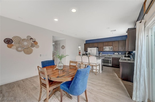 dining space with sink and light hardwood / wood-style floors