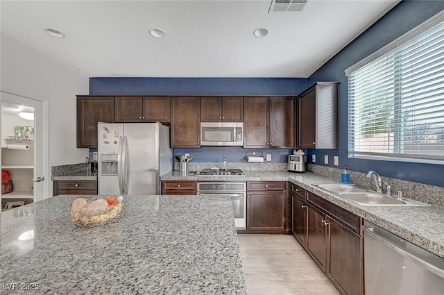 kitchen featuring light hardwood / wood-style floors, appliances with stainless steel finishes, light stone countertops, and sink