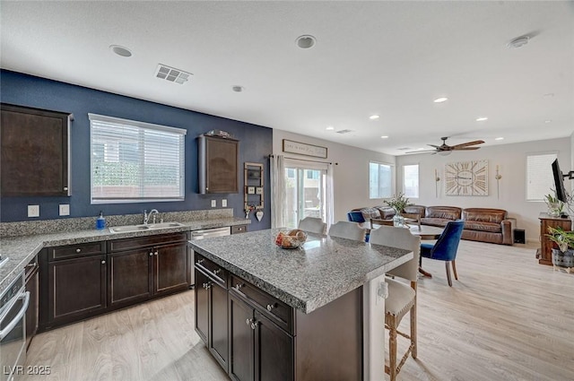 kitchen featuring a kitchen island, sink, dark brown cabinetry, and light hardwood / wood-style flooring