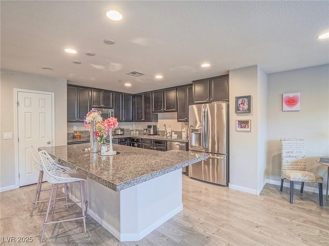 kitchen featuring sink, a breakfast bar area, light wood-type flooring, appliances with stainless steel finishes, and a kitchen island