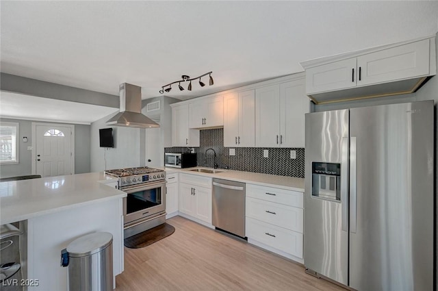 kitchen featuring white cabinetry, island exhaust hood, appliances with stainless steel finishes, and tasteful backsplash