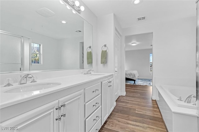 bathroom with hardwood / wood-style flooring, vanity, and a tub