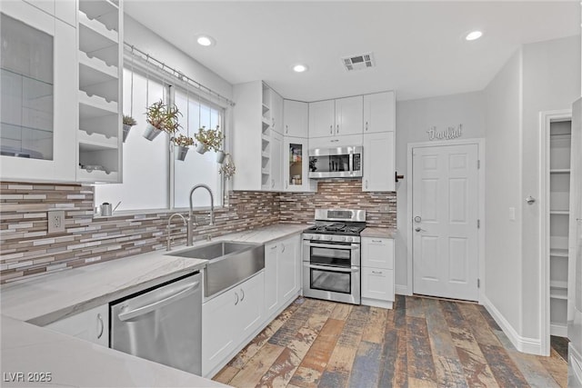 kitchen with sink, white cabinetry, stainless steel appliances, dark hardwood / wood-style flooring, and decorative backsplash