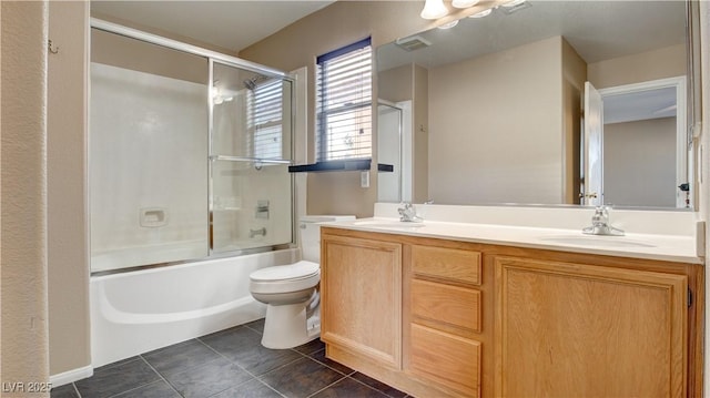 full bathroom featuring tile patterned flooring, vanity, bath / shower combo with glass door, and toilet