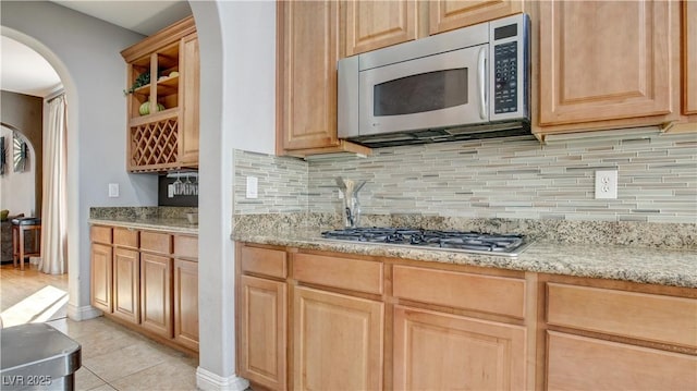 kitchen featuring light brown cabinetry, light stone counters, light tile patterned floors, stainless steel appliances, and decorative backsplash