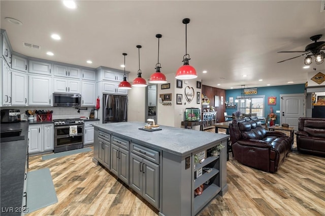 kitchen with pendant lighting, gray cabinetry, stainless steel appliances, light hardwood / wood-style floors, and a kitchen island