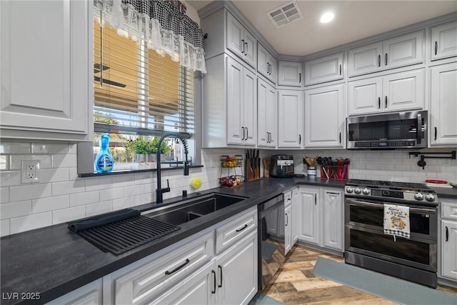 kitchen featuring stainless steel appliances, sink, light hardwood / wood-style flooring, and decorative backsplash