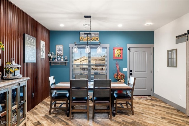 dining space featuring a barn door and light hardwood / wood-style flooring