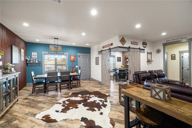 dining space with a barn door and light wood-type flooring