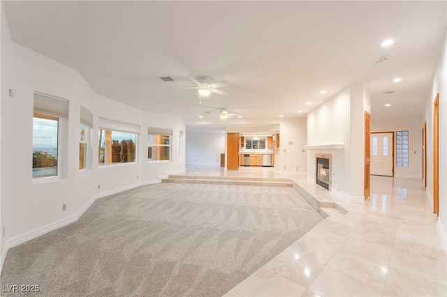 unfurnished living room with ceiling fan and a fireplace