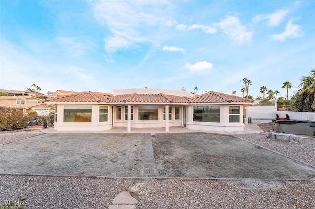 rear view of house featuring a hot tub and a patio