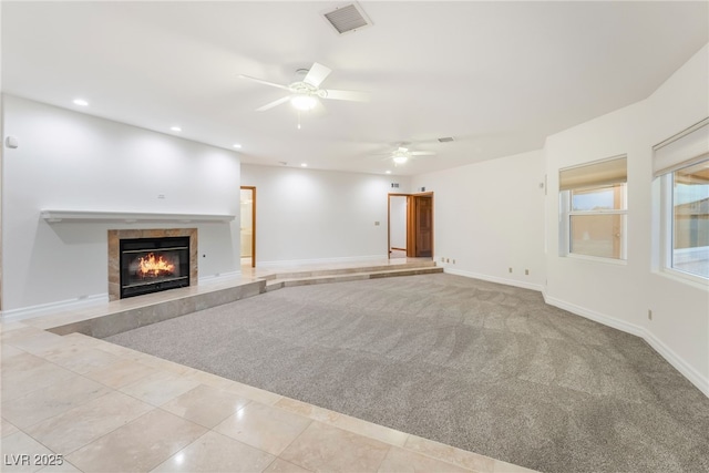 unfurnished living room with a fireplace, light colored carpet, and ceiling fan