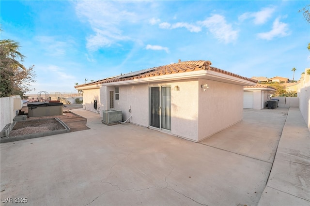 back of property with a hot tub, central AC, and a patio area