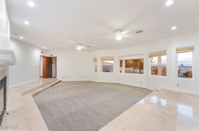 unfurnished living room featuring a tiled fireplace, light carpet, and ceiling fan