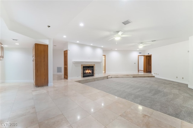 unfurnished living room featuring ceiling fan, a fireplace, and light carpet