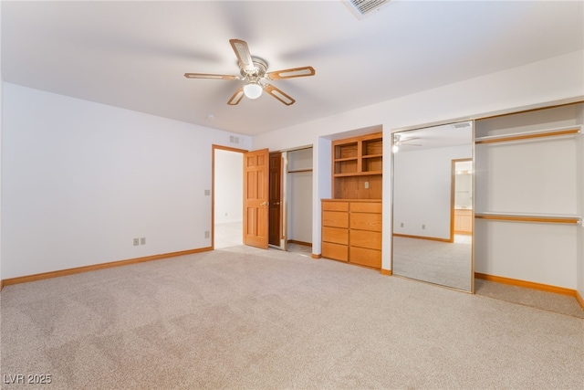 unfurnished bedroom with carpet floors, two closets, and ceiling fan