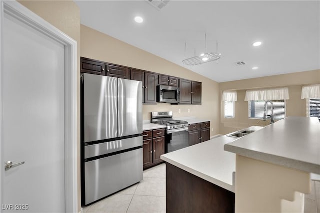 kitchen featuring dark brown cabinetry, lofted ceiling, sink, light tile patterned floors, and appliances with stainless steel finishes