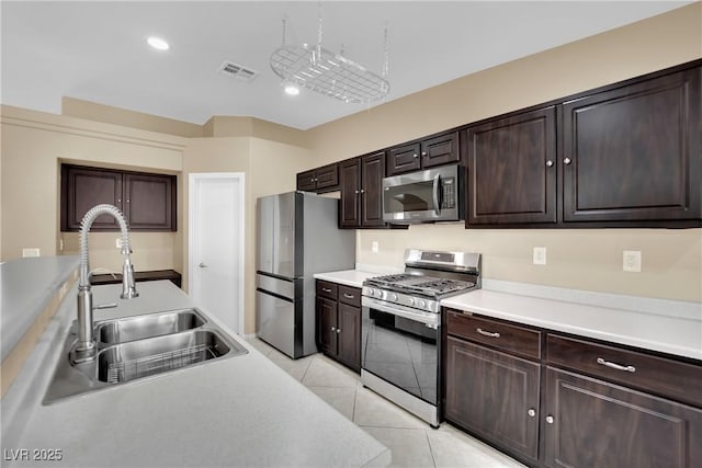 kitchen with sink, dark brown cabinets, light tile patterned flooring, and appliances with stainless steel finishes