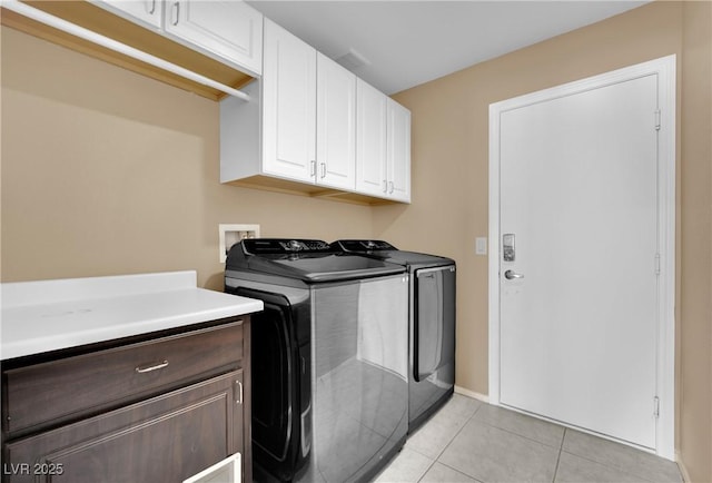 laundry room featuring washer and dryer, light tile patterned floors, and cabinets