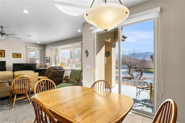 tiled dining area with a textured ceiling and ceiling fan