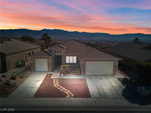 view of front of property featuring a garage, a mountain view, and cooling unit