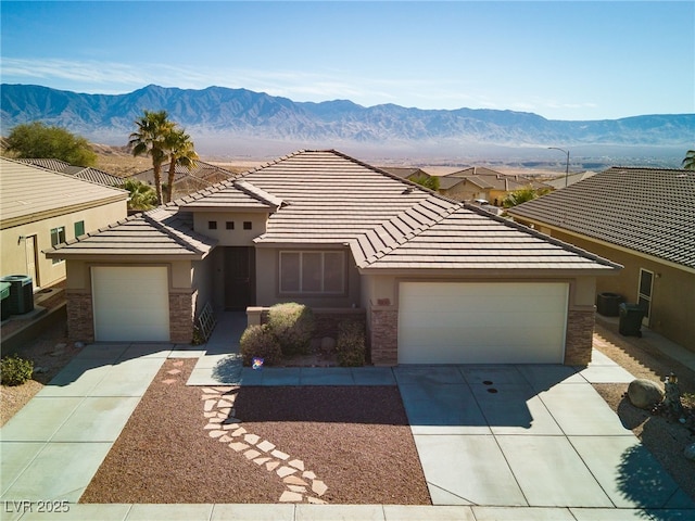 view of front of property with a mountain view, a garage, and central air condition unit