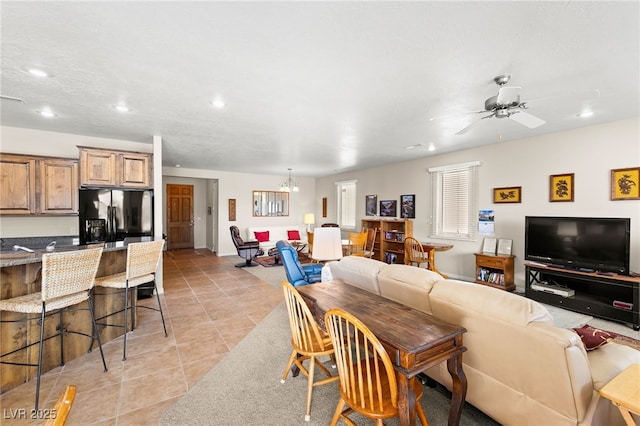 living room featuring ceiling fan with notable chandelier and light tile patterned floors