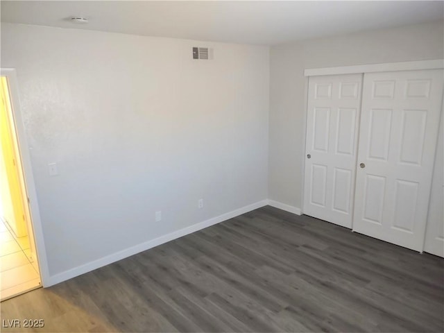 unfurnished bedroom with a closet and dark hardwood / wood-style floors