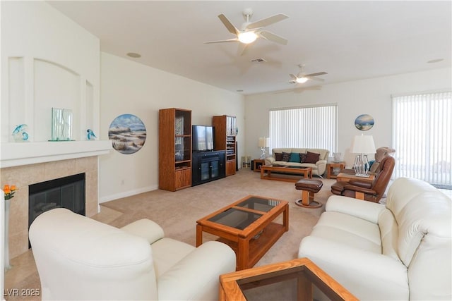 living room with light carpet, a tiled fireplace, and ceiling fan