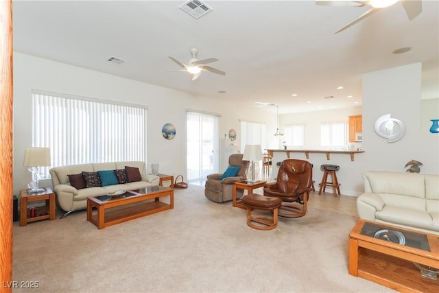 living room featuring a healthy amount of sunlight, light carpet, and ceiling fan