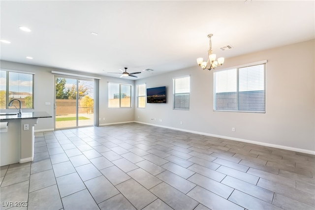 unfurnished living room featuring sink, ceiling fan with notable chandelier, and light tile patterned floors