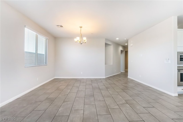 spare room featuring an inviting chandelier