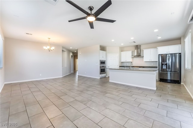 kitchen featuring white cabinetry, appliances with stainless steel finishes, a center island with sink, and wall chimney range hood