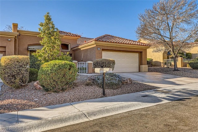 mediterranean / spanish house with a tile roof, stucco siding, concrete driveway, a gate, and a garage