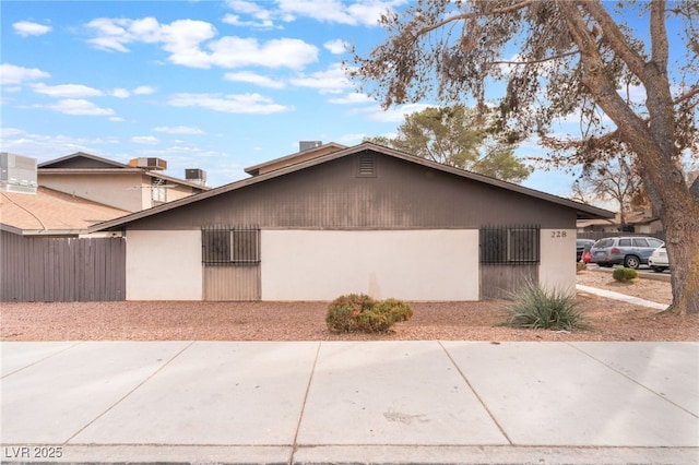 view of property exterior with driveway, an attached garage, fence, cooling unit, and stucco siding