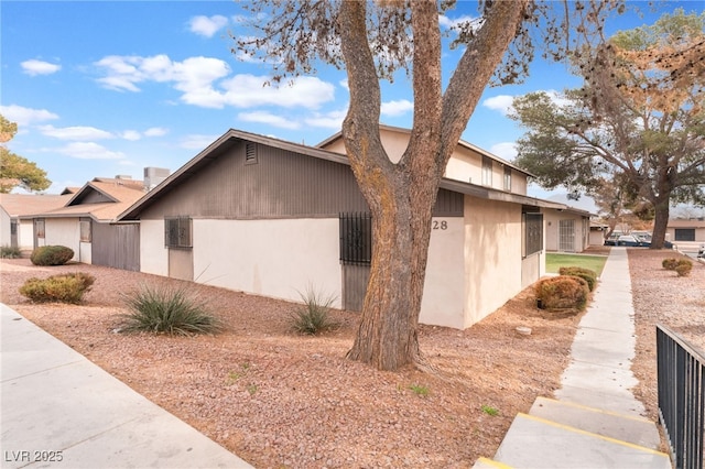 view of side of home with fence and stucco siding