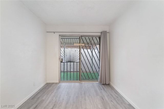 empty room with light wood-type flooring and baseboards