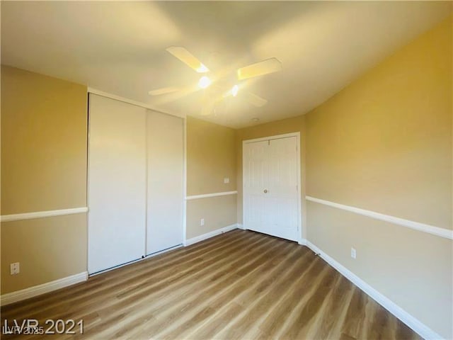 unfurnished bedroom featuring hardwood / wood-style flooring, a closet, and ceiling fan