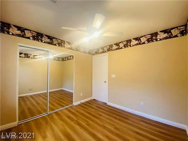 unfurnished bedroom with hardwood / wood-style flooring, ceiling fan, and a closet