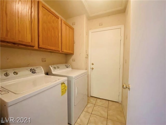 laundry area with cabinets, light tile patterned flooring, and washing machine and clothes dryer