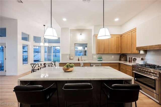 kitchen featuring a kitchen island, appliances with stainless steel finishes, a breakfast bar, and hanging light fixtures