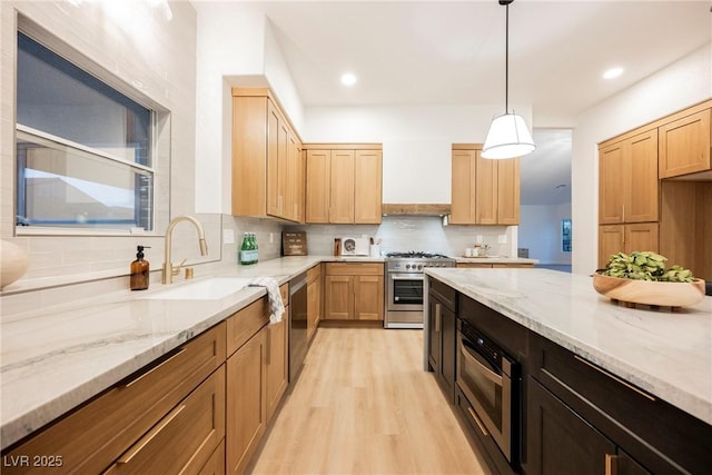 kitchen featuring premium range hood, sink, hanging light fixtures, light stone counters, and stainless steel appliances