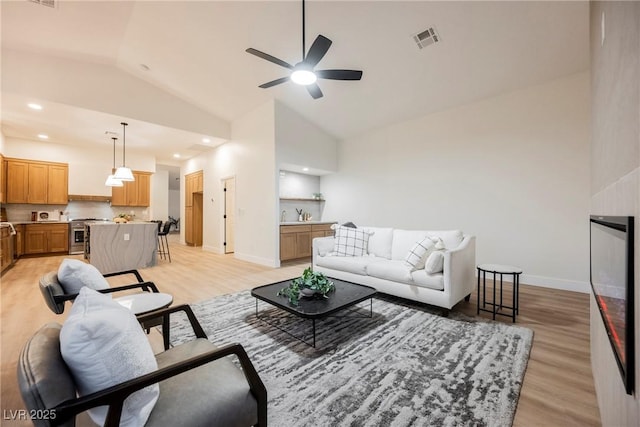 living room with ceiling fan, high vaulted ceiling, sink, and light hardwood / wood-style floors